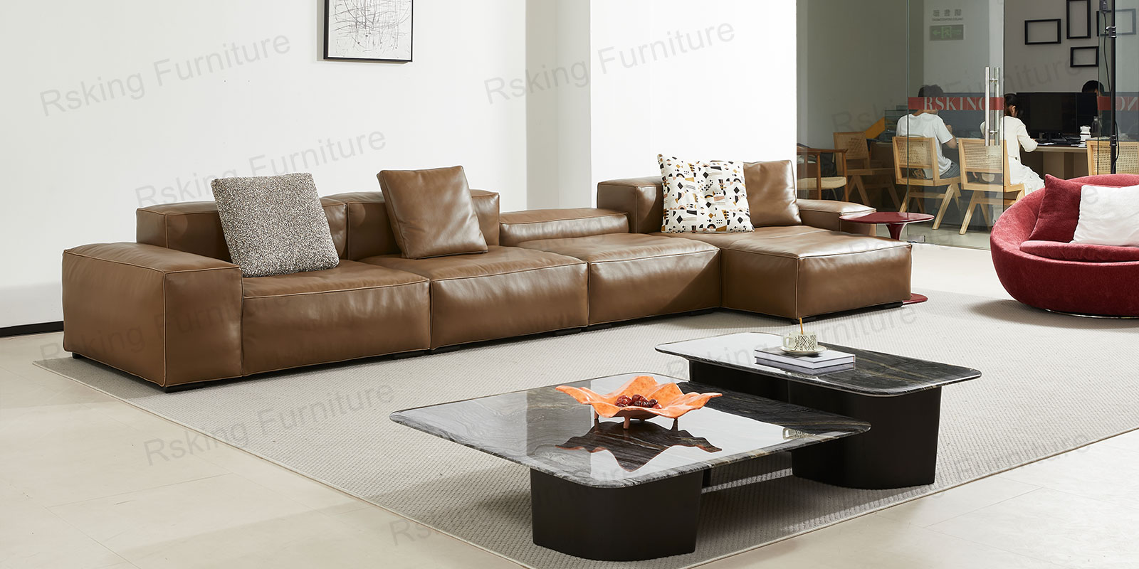 Long brown sectional sofa with a low central back section and chaise beside dark stone coffee tables