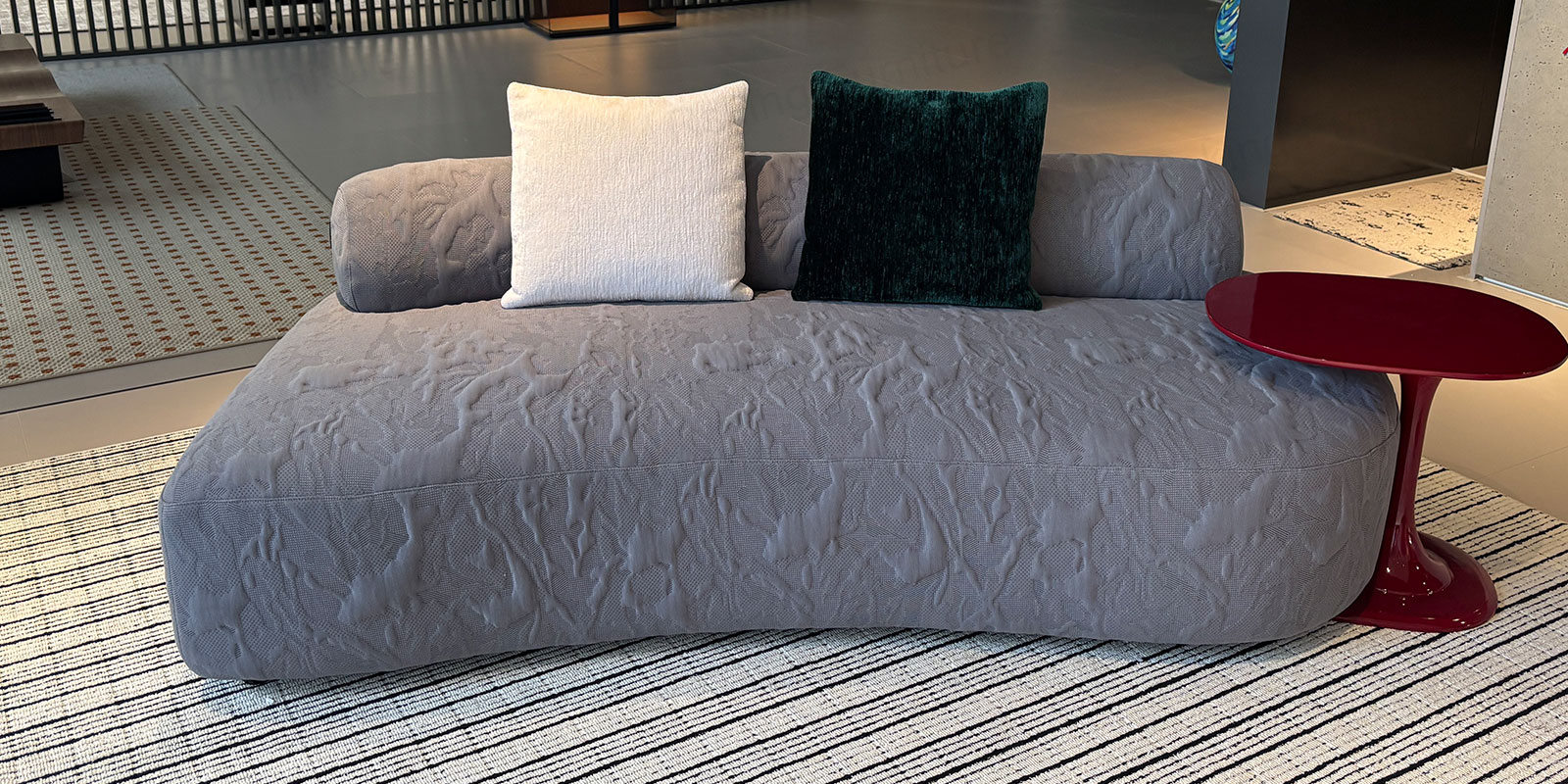 RSK2422 gray jacquard fabric sofa in a showroom with a red side table and contrasting throw pillows