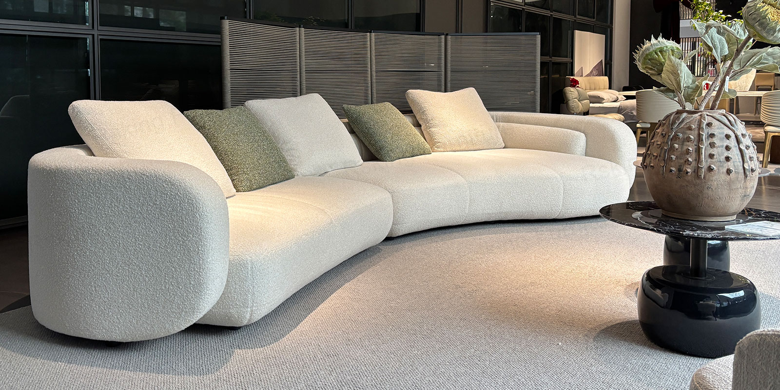 Angled view of the cream chenille sectional sofa showing its rounded arm, low back and softly curved seat front