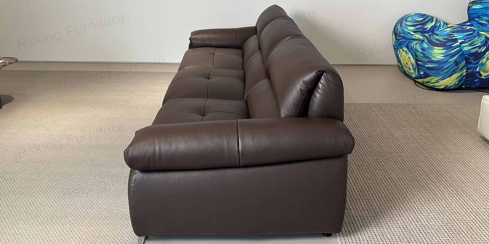 Olive green leather sofa in a showroom with one seat extended beside round wood and stone tables