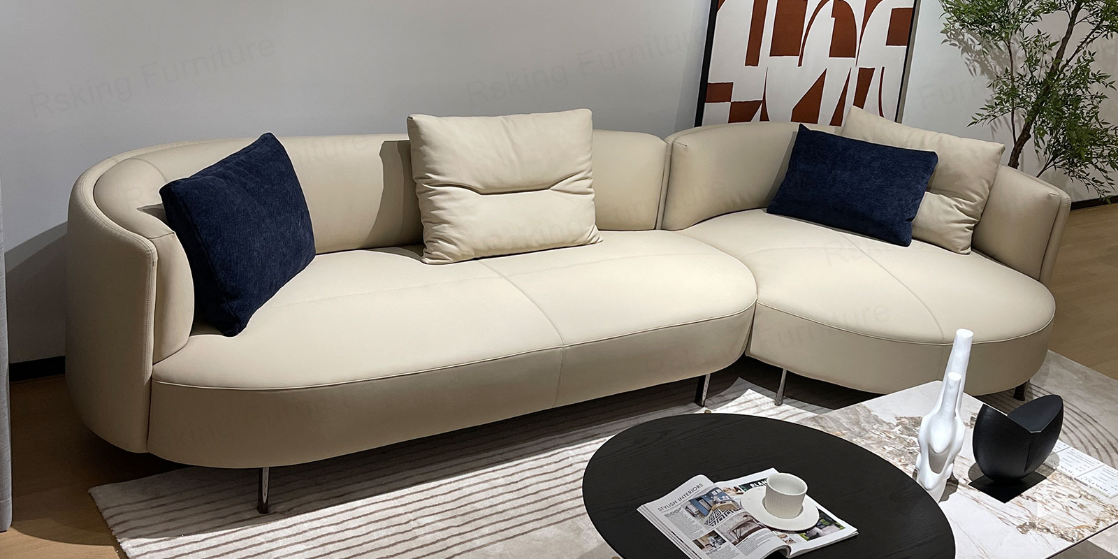 Elevated view of the cream curved sofa showing broad seats, rounded chaise and contrasting navy pillows