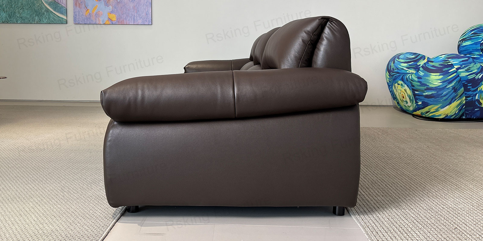 Elevated side view of the brown leather sofa showing layered back cushions and stitched seats