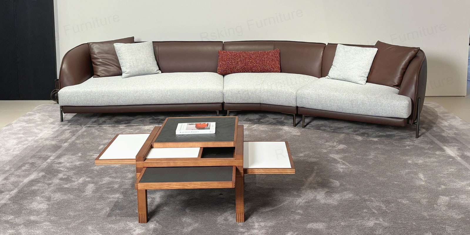 Brown leather and pale fabric sofa with a curved back, mixed accent pillows and slender dark metal legs