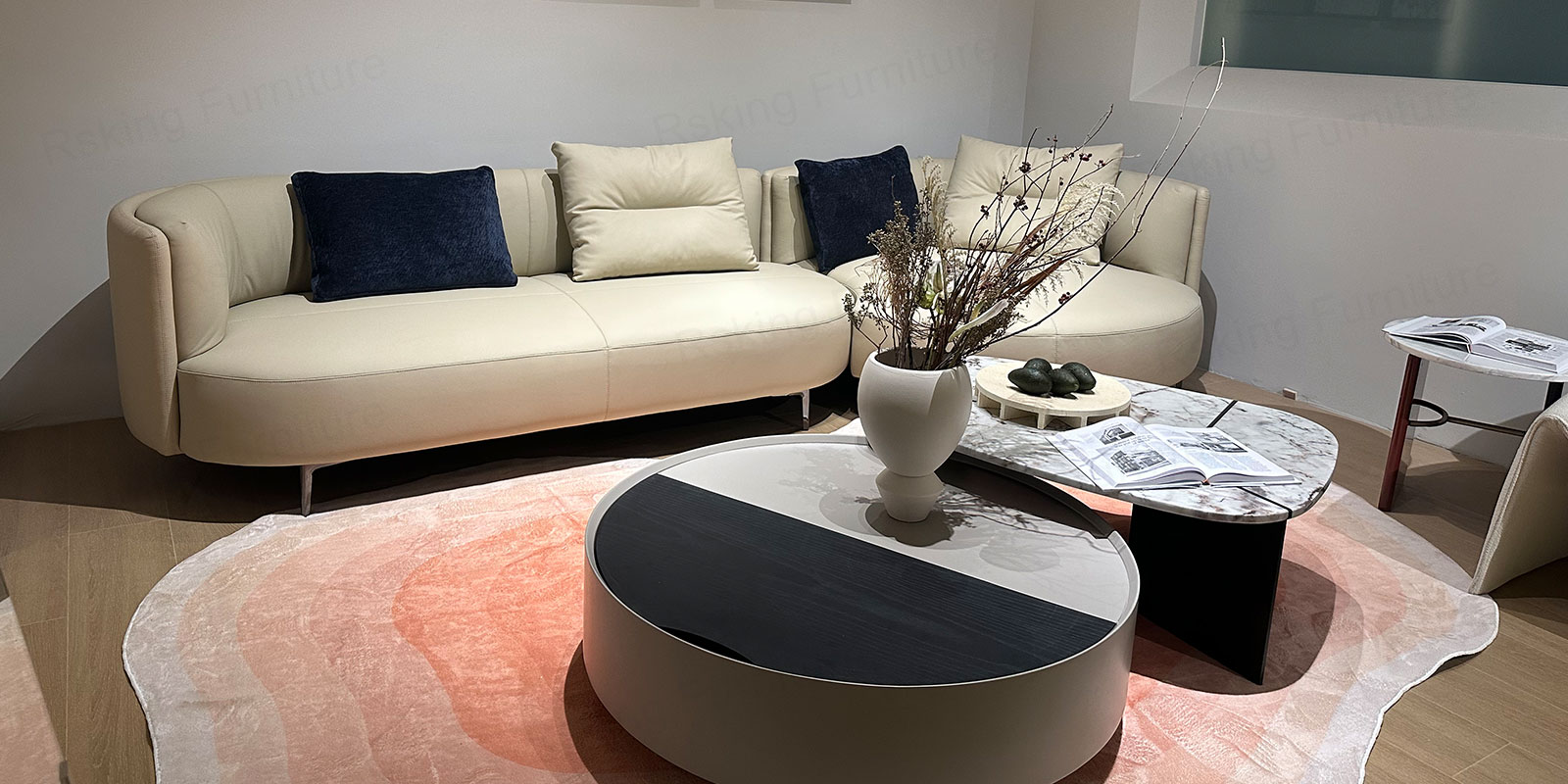 Cream curved sofa styled with round coffee tables, navy pillows and a pink patterned rug